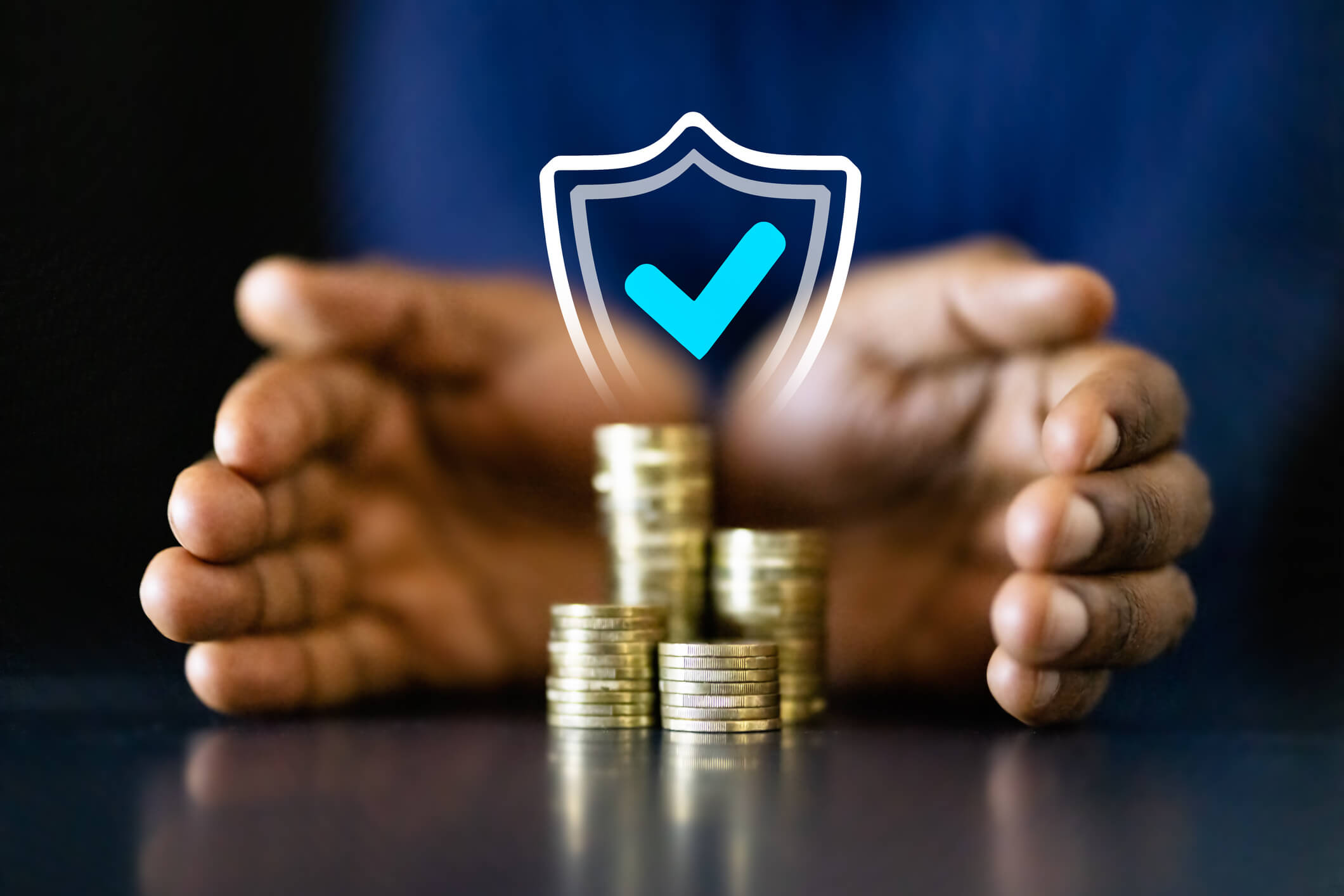 Hands protecting stacked coins with shield icon.