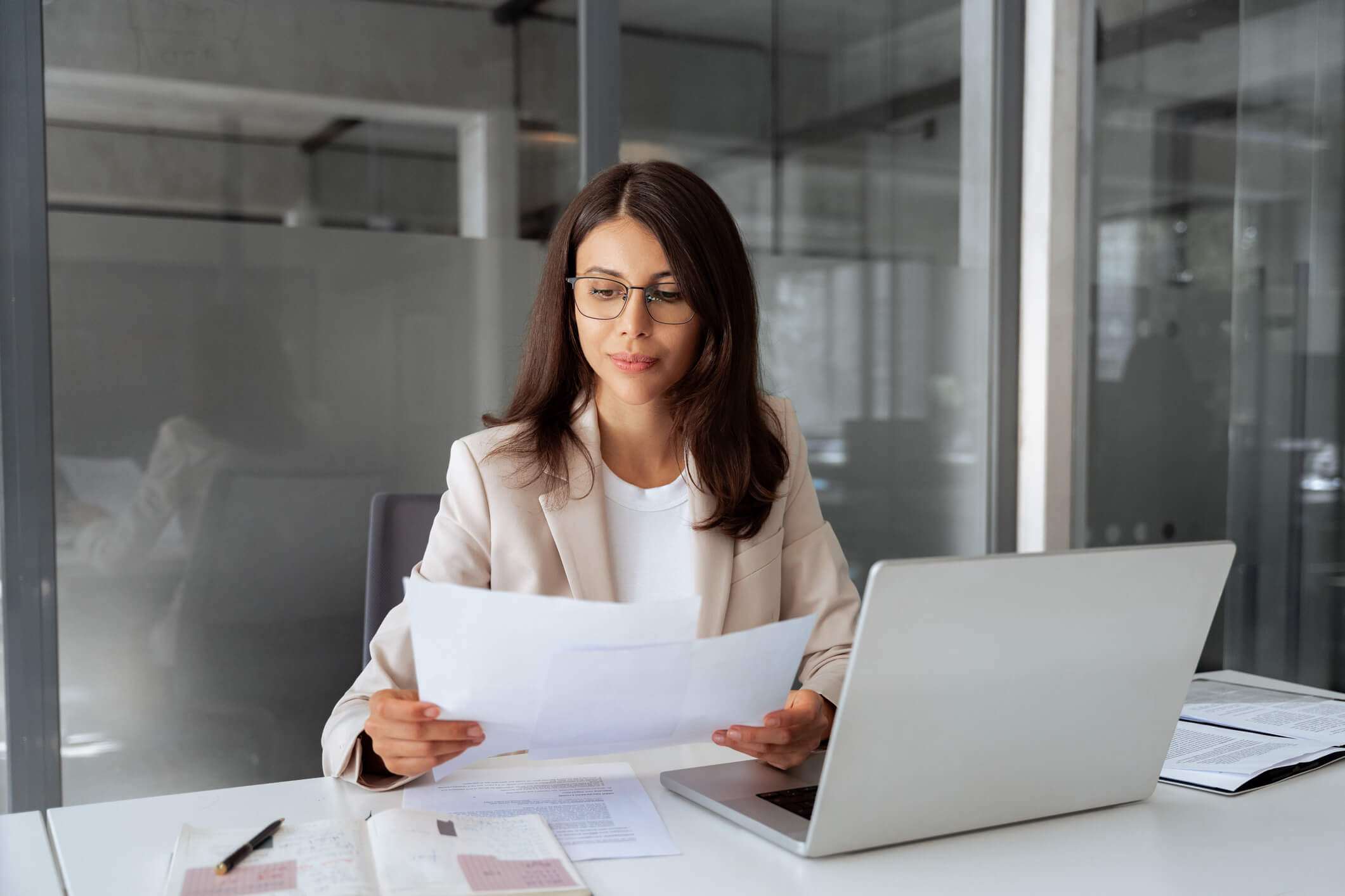 Businesswoman reading documents at office desk.