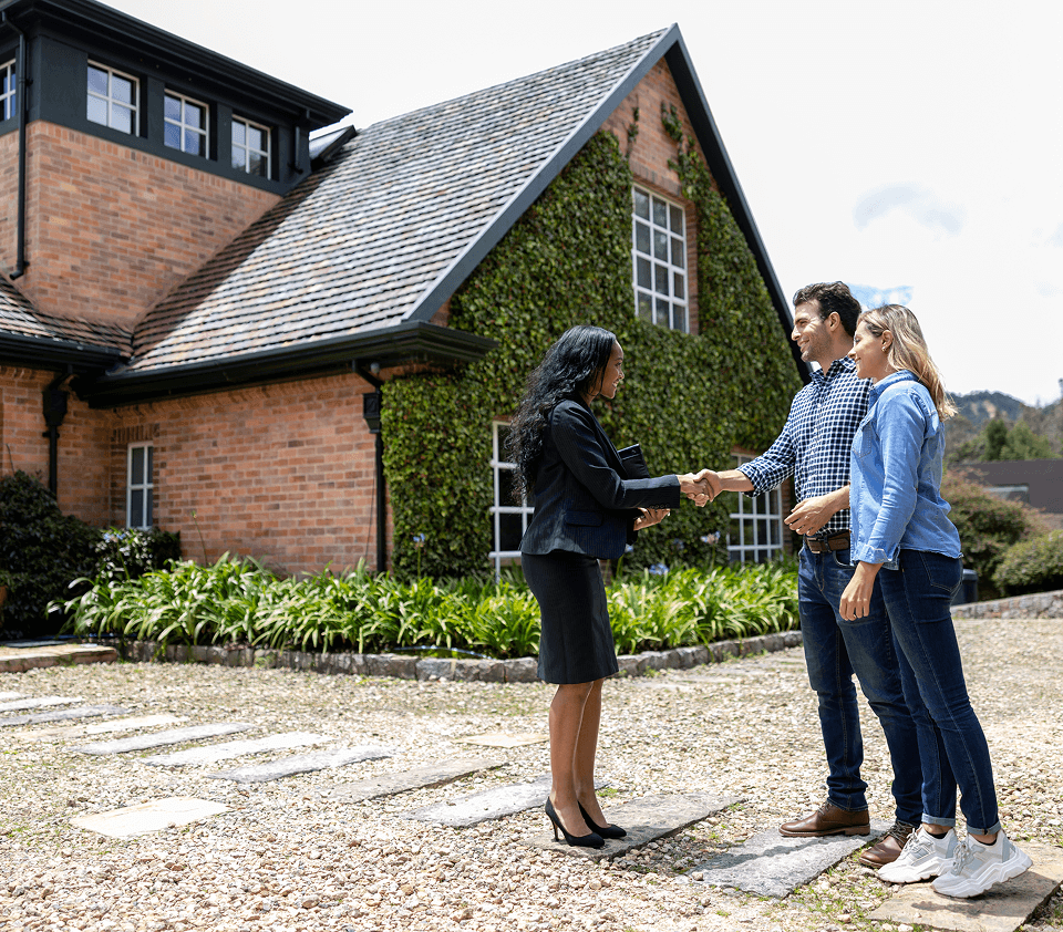 Couple meeting realtor outside a house.